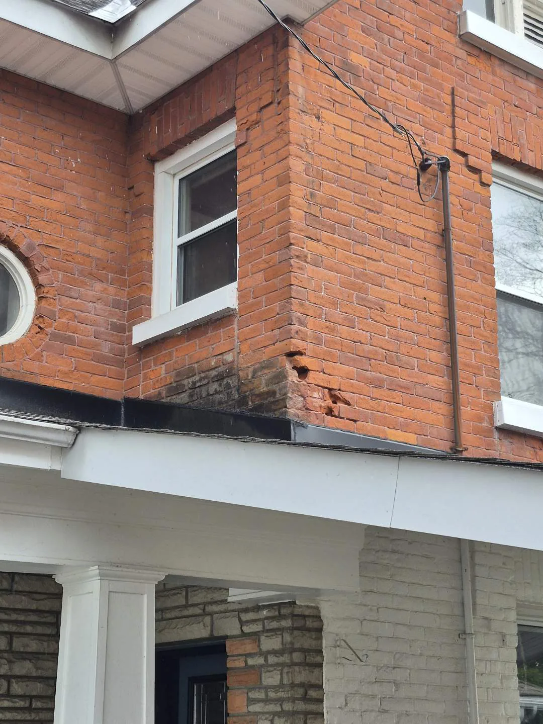 Damaged and spalling brick around a century home corner before repair